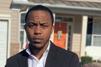 Sociology graduate Peterson stands outside wearing a suit