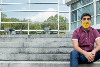 Bhavik sits on the steps of Engineering Hall wearing a mask.