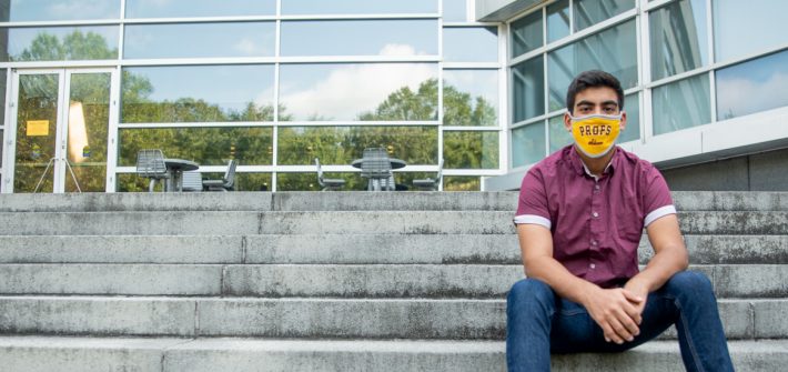 Bhavik sits on the steps of Engineering Hall wearing a mask.