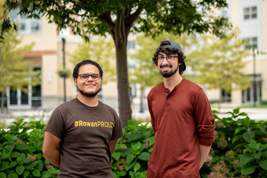 Luis and Nick standing in front of foliage.
