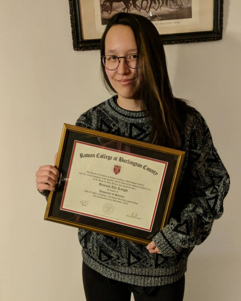 Hannah holding a her associate degree diploma.