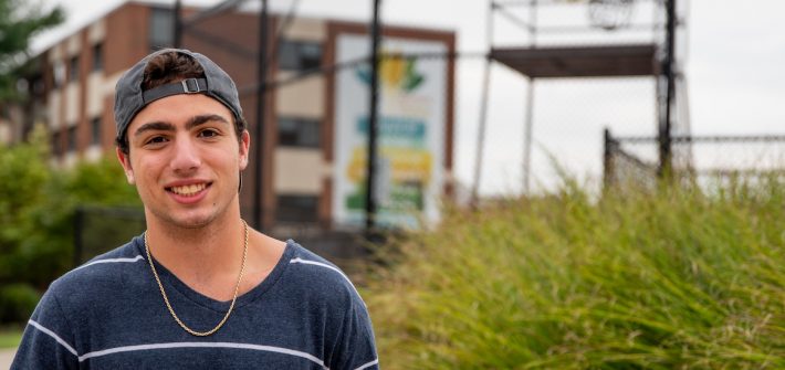 Spencer wearing a hat and standing outside on campus.