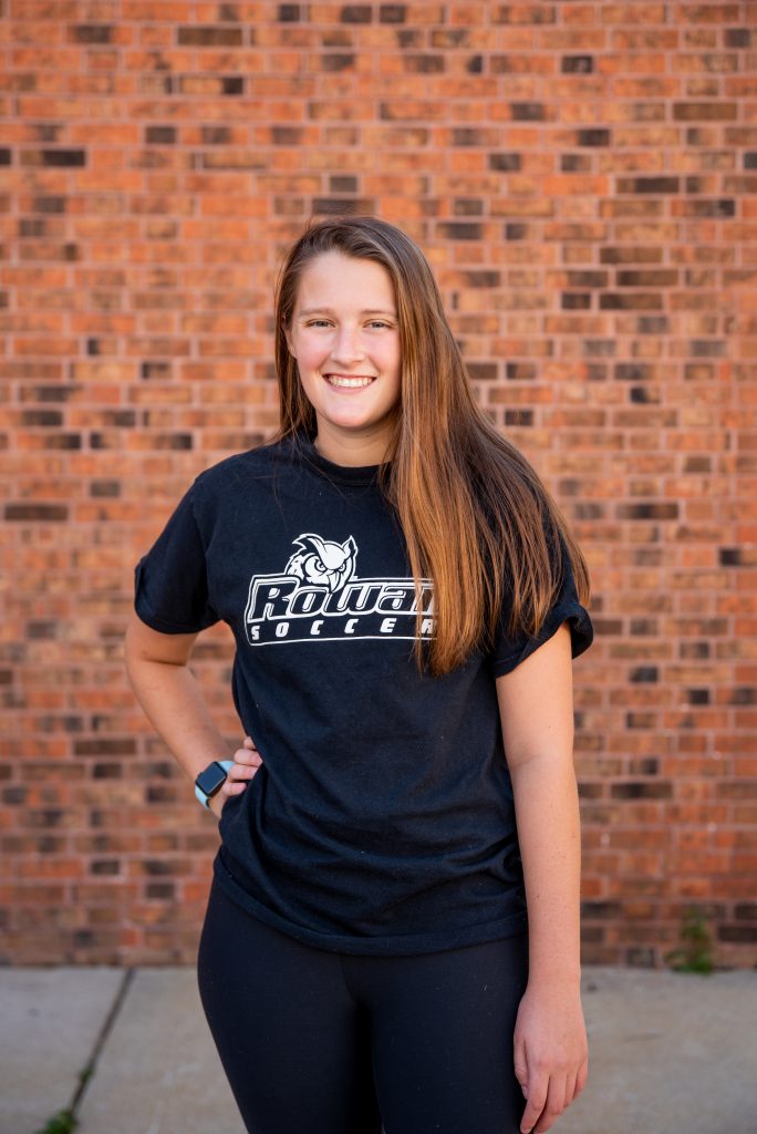 Catie standing in front of a brick wall.