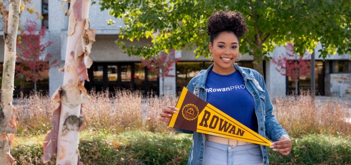 College of Education student Cheyenne holds a pennant on campus.
