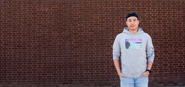 Enkee standing in front of brick wall.