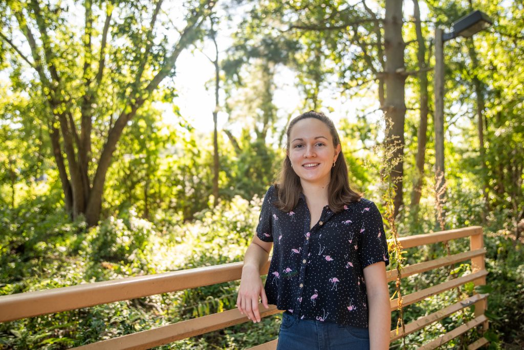 Jennifer leaning against the trail bridge on campus.