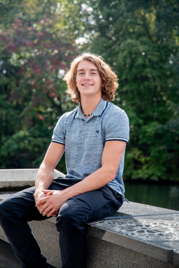 Engineering student Nicholas Kreuz poses sitting down with his hands on top of one another. 