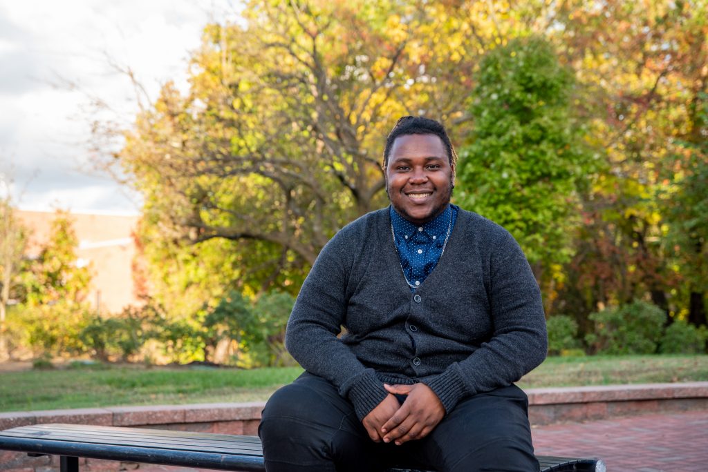 TJ sitting on a bench outside on campus.