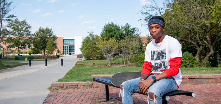 McCarly sits on a bench on campus outside.