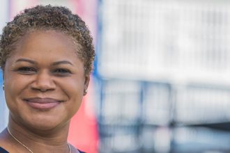 Erica Watson Brown stands outside of a playground.