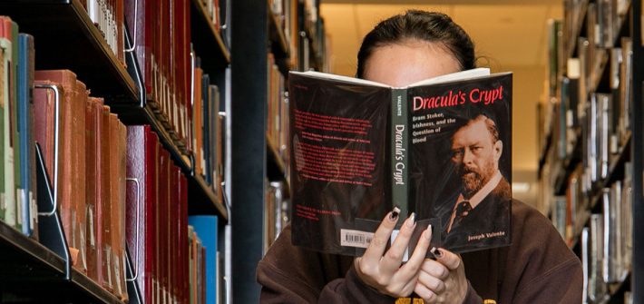 Student reads a book in the stacks of Campbell Library.