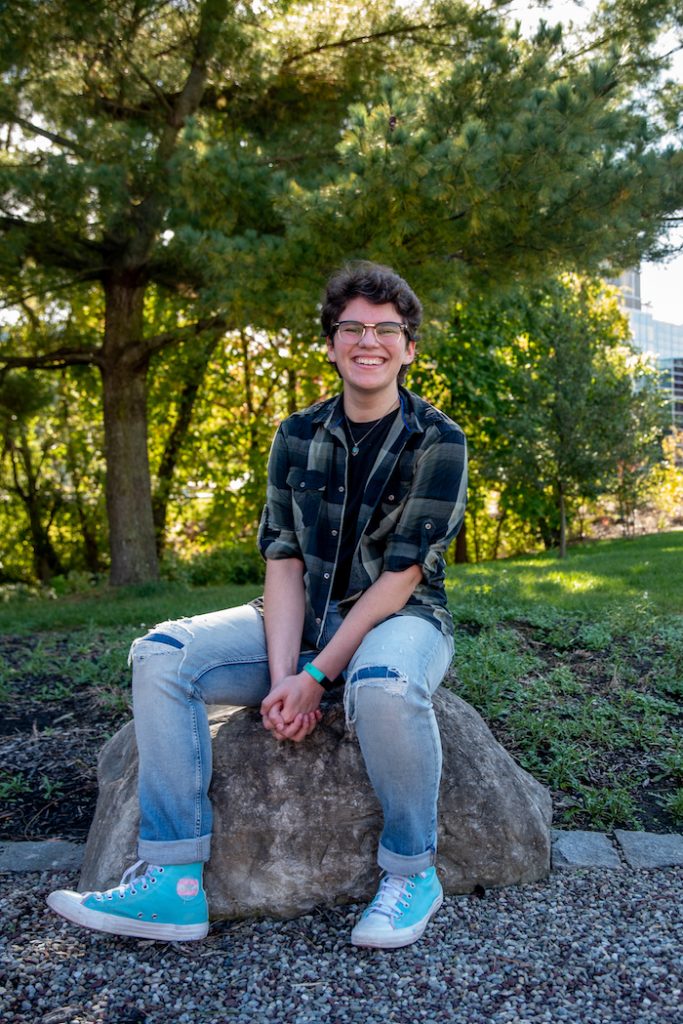 Elliot sitting on a rock outside on campus.