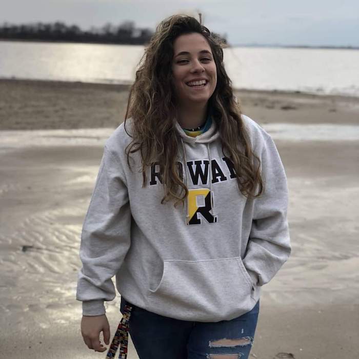 Melissa wearing a Rowan sweatshirt while walking on the beach.