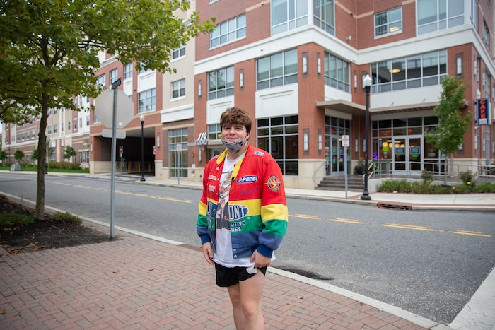 Nick posing by 114 Victoria wearing a rainbow jacket.