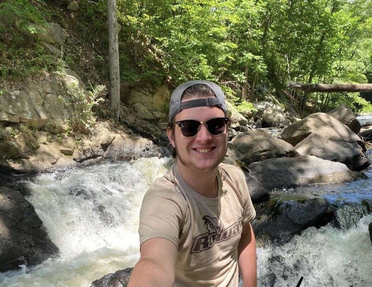 John poses in front of a waterfall wearing a Rowan shirt.