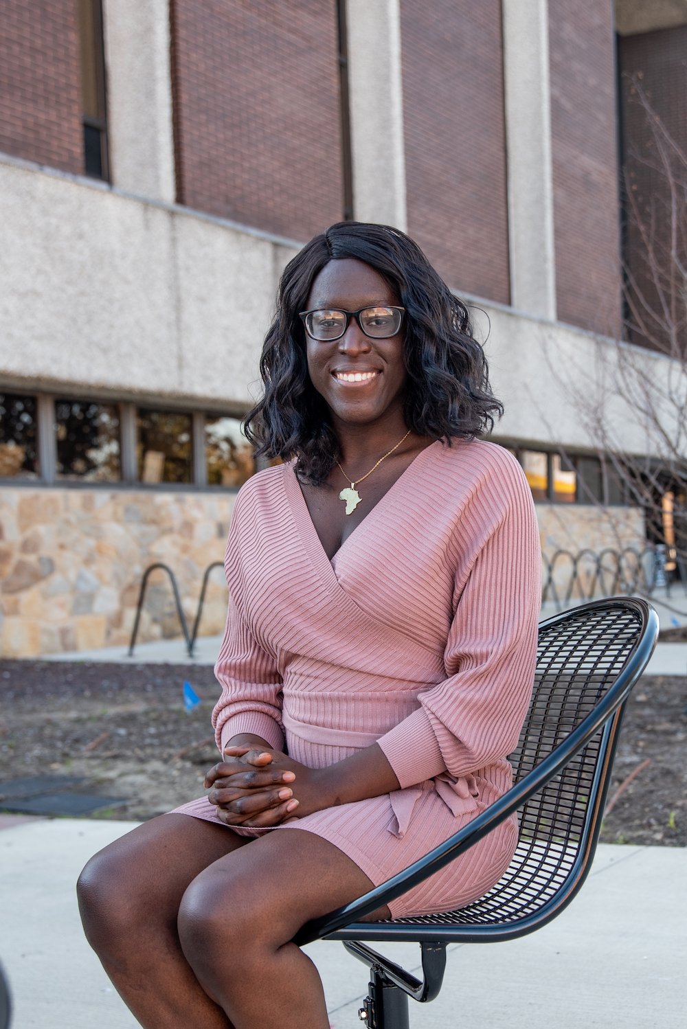 Tiara Gbeintor smiles sitting down outside in front of Robinson hall. 