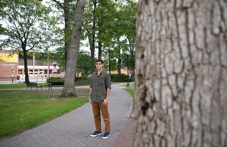 Marco stands in a walking path along campus.