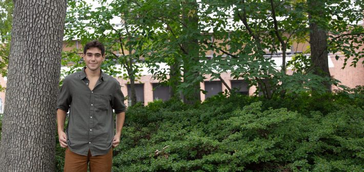 Marco stands in a wooded section of campus.