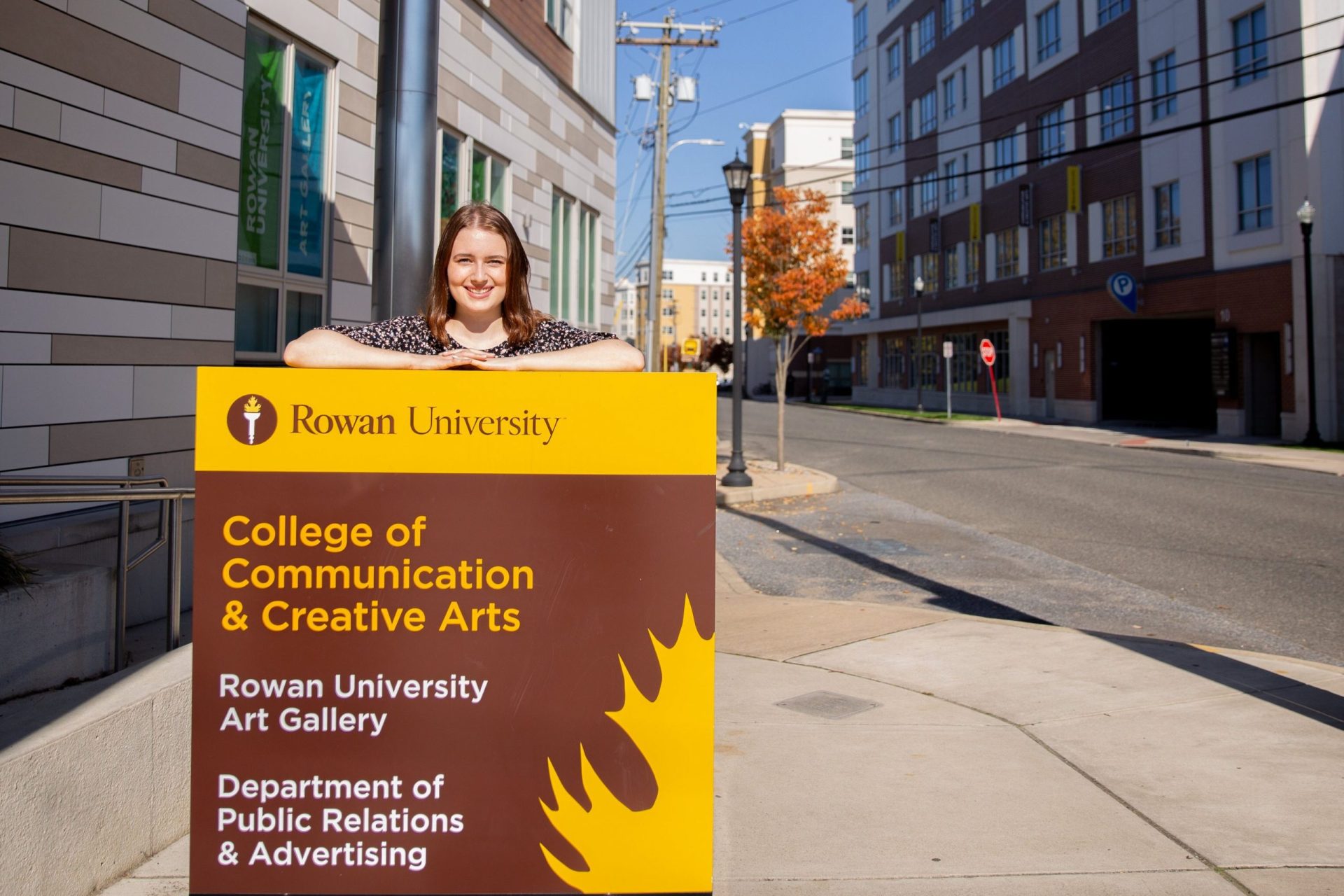 Jessica poses with a sign in front of 301 high street.