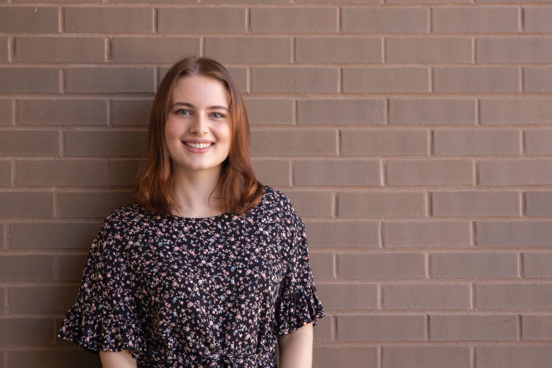 Jessica poses against a brick wall.