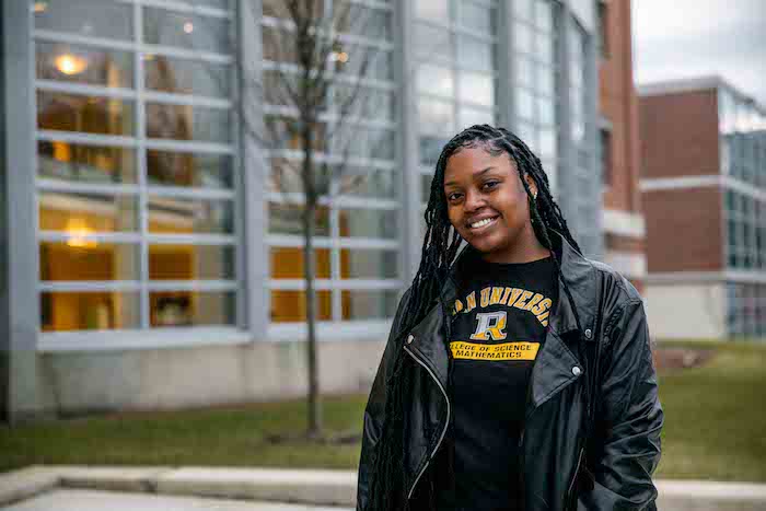 Ylanda wearing a Rowan shirt and posing outside the Campbell Library.