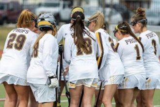 Rowan's Women's Lacrosse players huddle on the field.