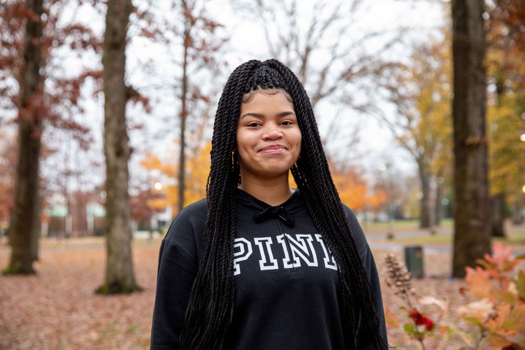 Photo of Shaleeyah with fall foliage behind.