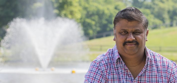 Ganesh smiles in front of a park area.