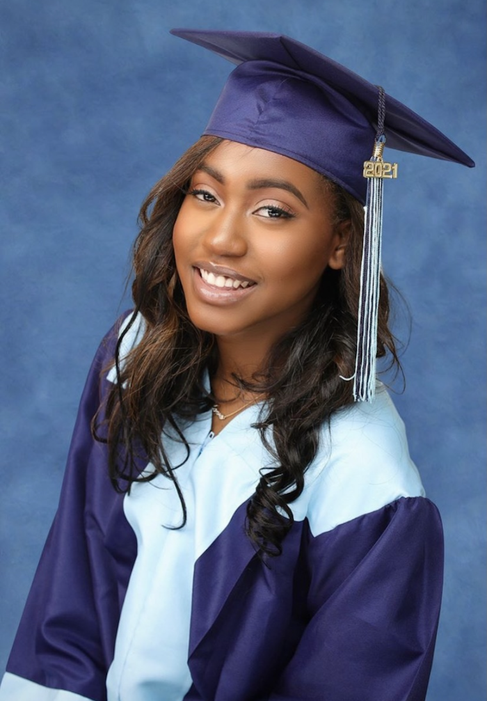 Mikia posing for a portrait photo in her high school graduation cap and gown.