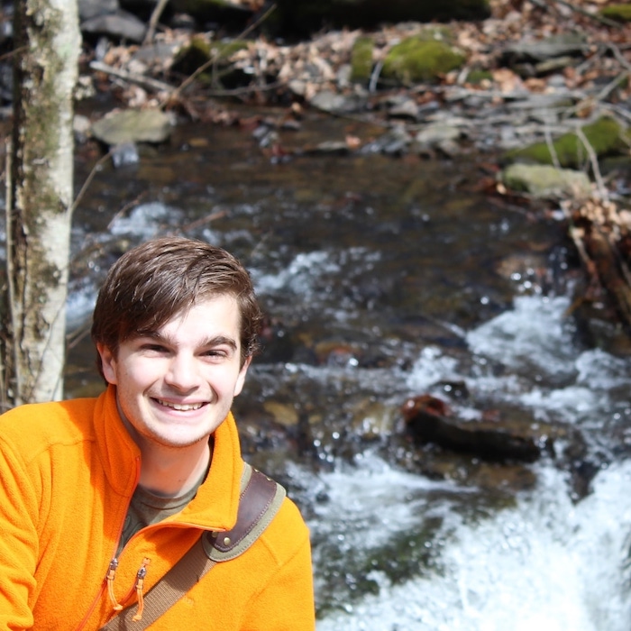 Paul smiling and posing in front of a stream.