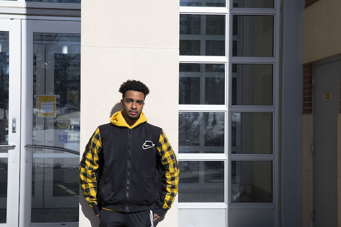 Bryce outside the Campbell library wearing a yellow and black jacket.