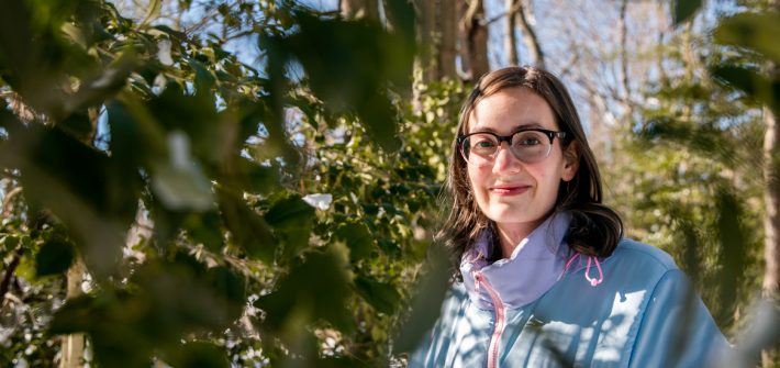 JoAnna standing in between a a tree.