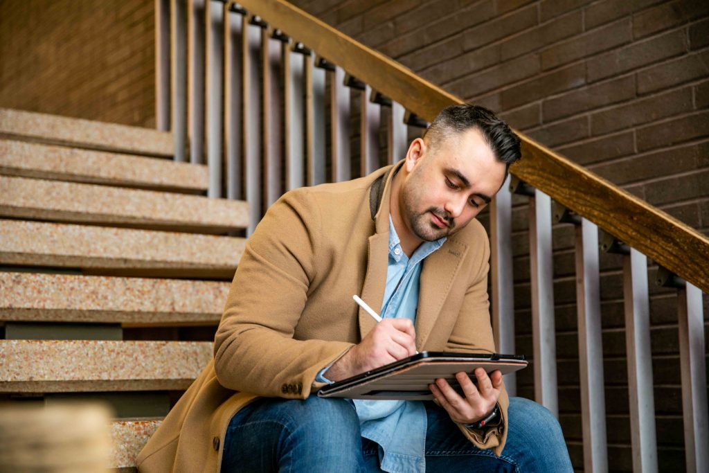 Jordan sitting on a set of stairs studying on his iPad.