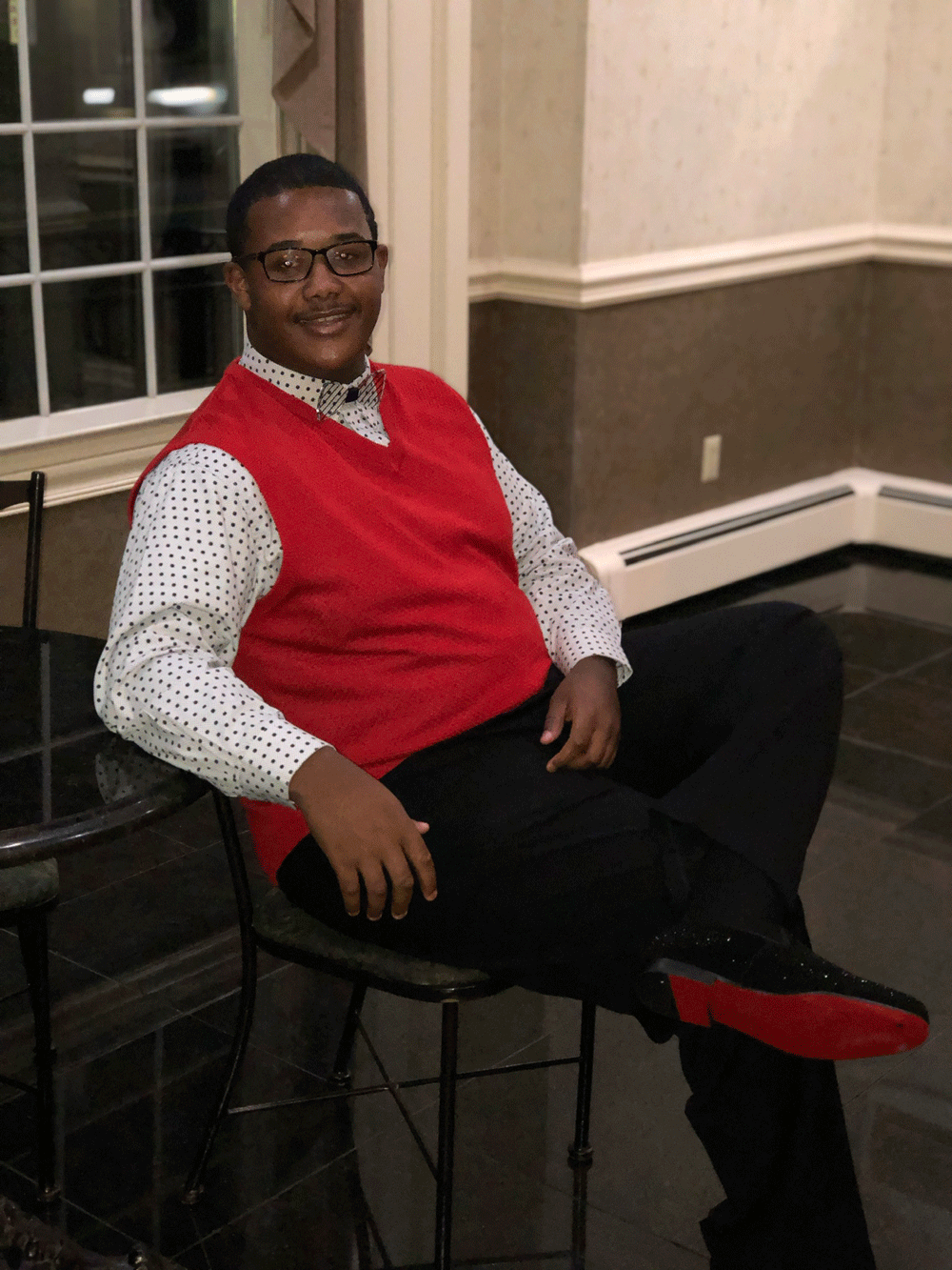 Jamar Green sits and smiles, wearing a red vest.