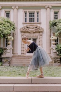 Paige in her ballet gear posing in front of an ornate building.