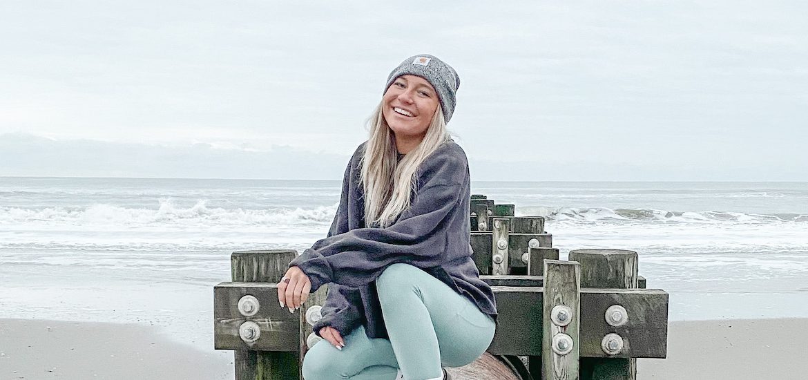 Autumn smiles, wears a hat at the beach.