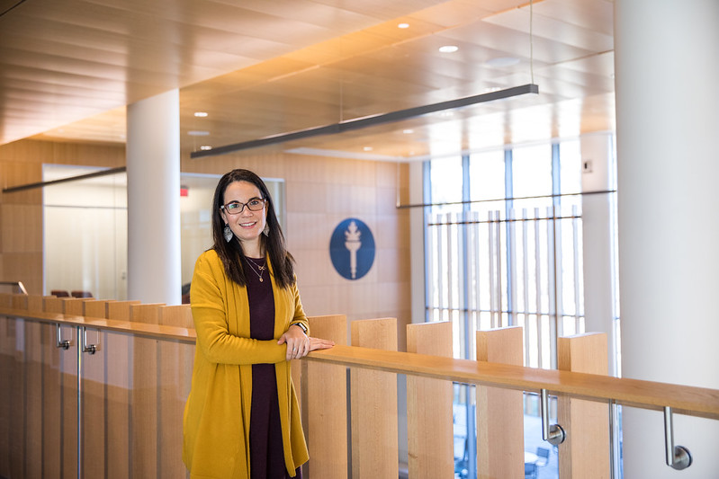 Dr. Susana stands by a railing inside Business Hall.