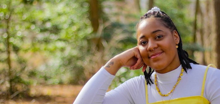 Ayanna sits down and leans against a bench on campus.