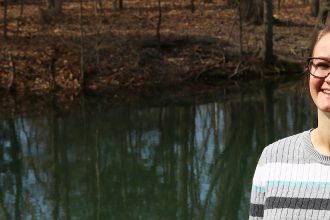 Allison stands and smiles next to a waterway on campus.