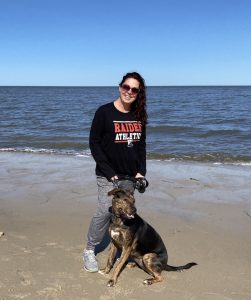 Heather standing on the beach with her dog. 