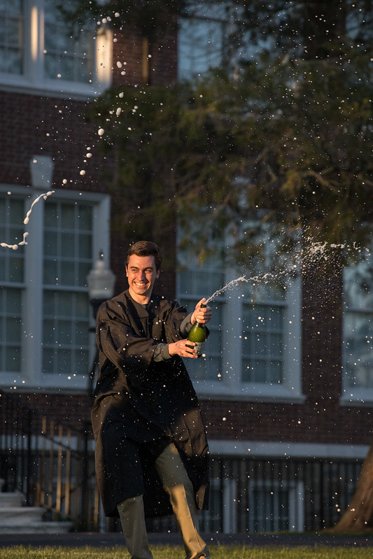 Student popping champagne in front of Bunce.