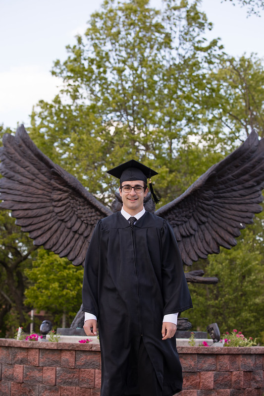 Student standing in front of the Prof statue so that the wings look like it is from the student.