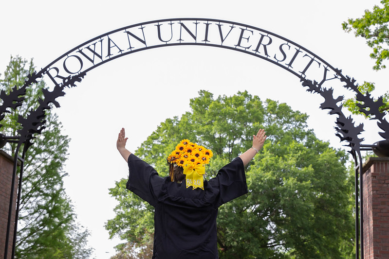 Student turned around showing cap off under the Rowan Arch.