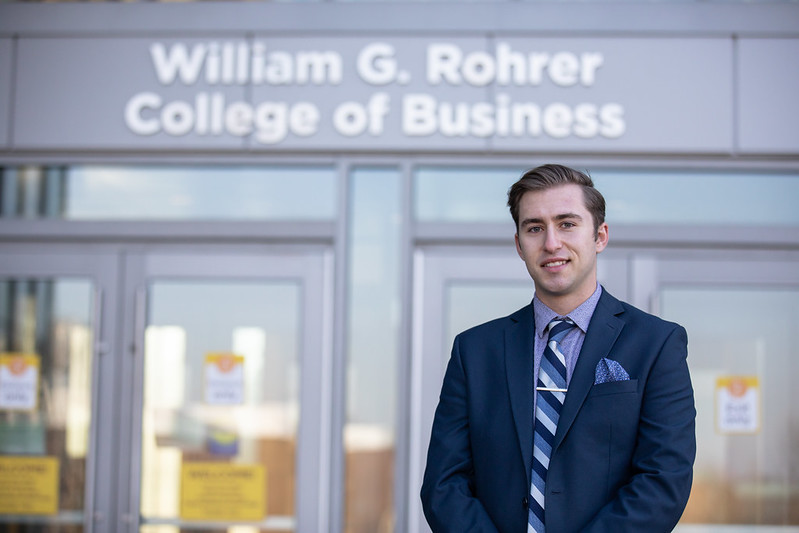 Brandon stands in front of the entrance to Business Hall.