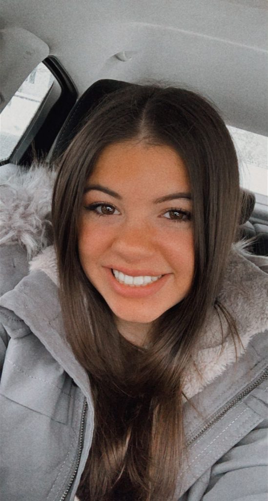 Selfie of Lizzie in the car with a gray winter coat on.