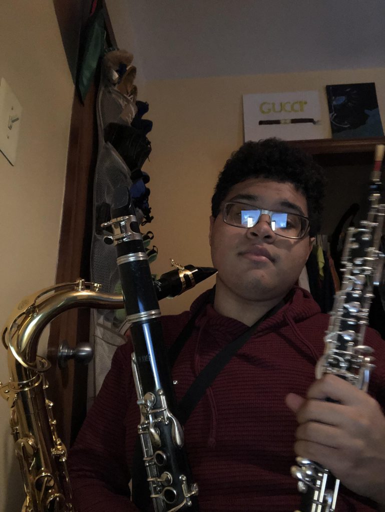 Selfie of Isaiah with a saxophone and two clarinets.