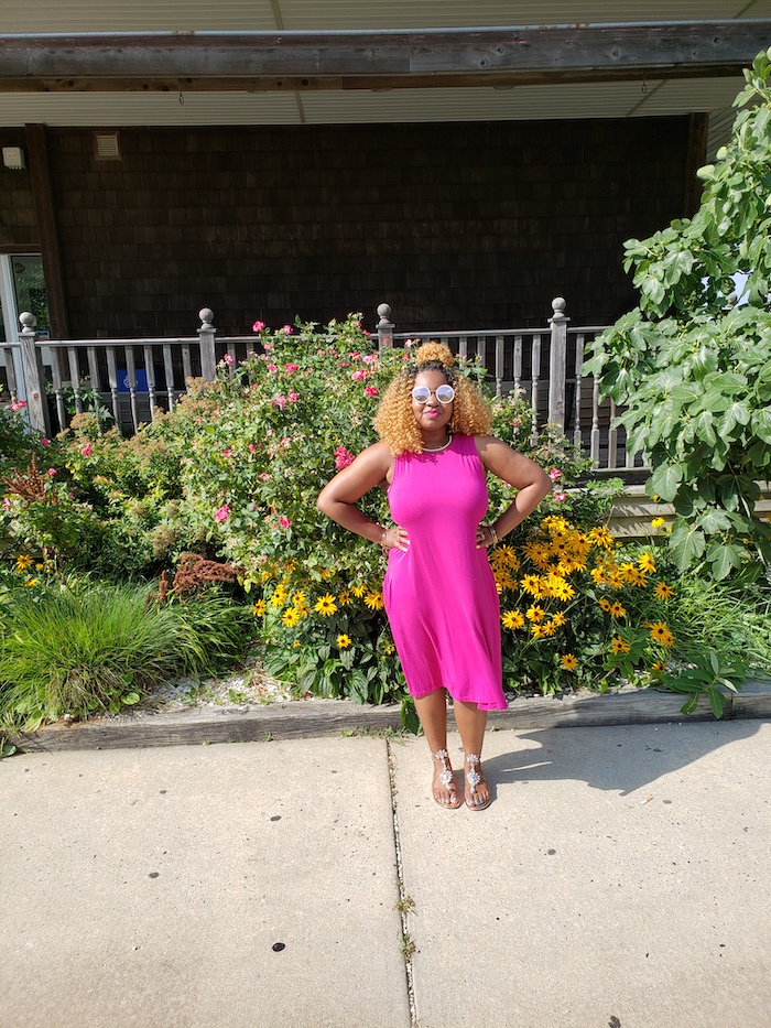 Rosetta posing for a photo in a hot pink sun dress and reflective sunglasses.