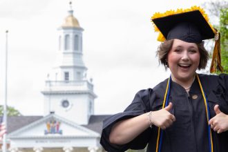 Student with cap and gown in front of Bunce.