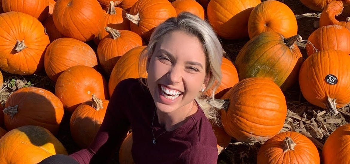 Outdoor photo of Sara smiling in a pumpkin patch.