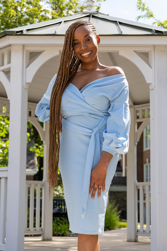 Esther smiles and stands in front of a campus gazebo.